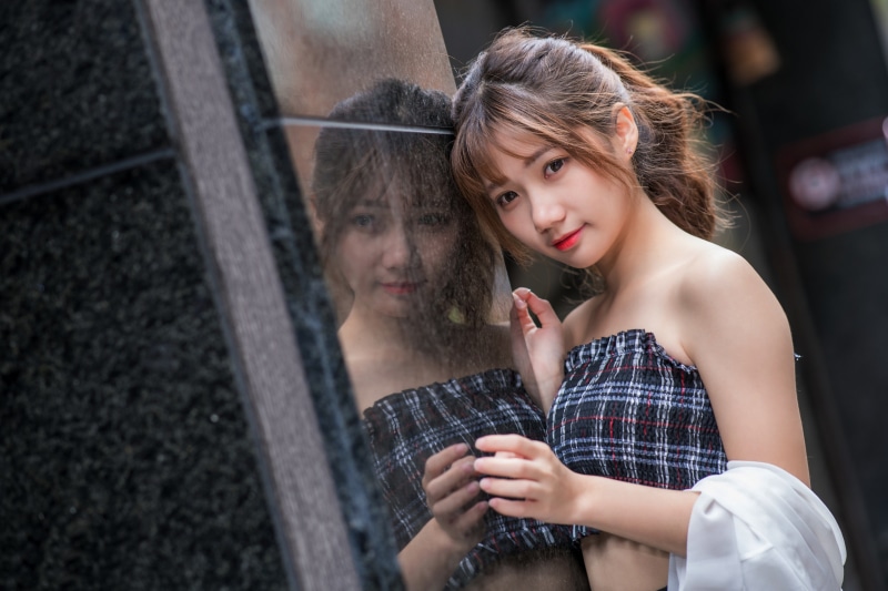 Asian woman with brown hair leaning on reflection