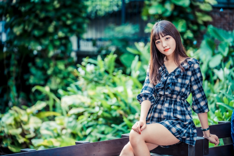 Asian woman in plaid dress sitting outdoors