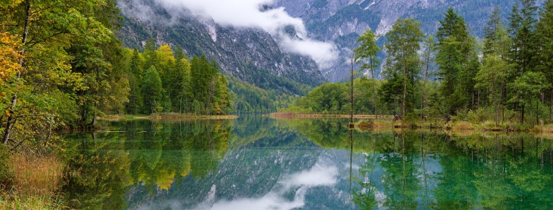 Panorama of a lake reflecting mountains and trees