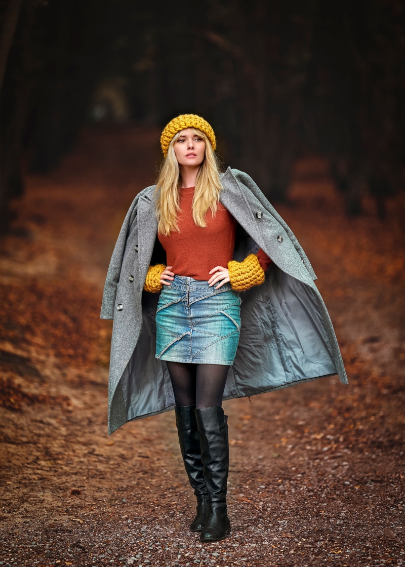 Blonde woman wearing winter hat, sweater, skirt, and coat