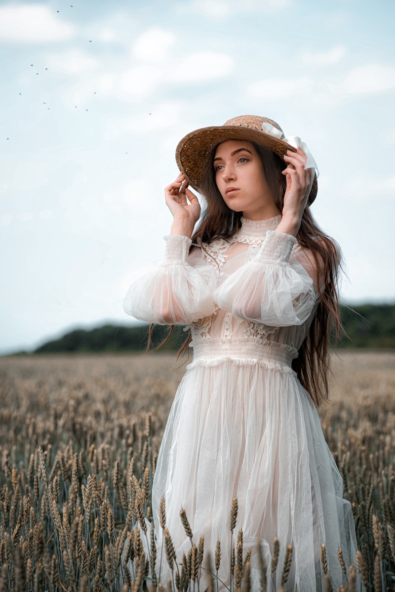 Woman in a straw hat and white dress in a wheat field