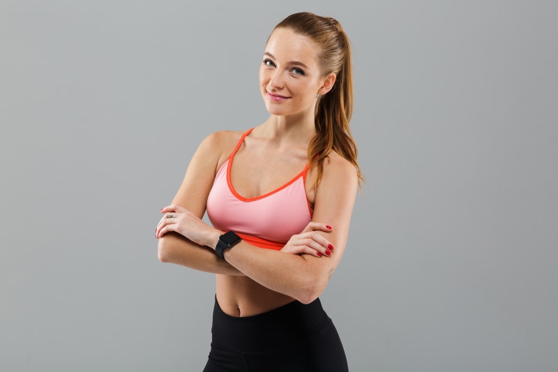Fitness woman in pink sports bra and black leggings posing