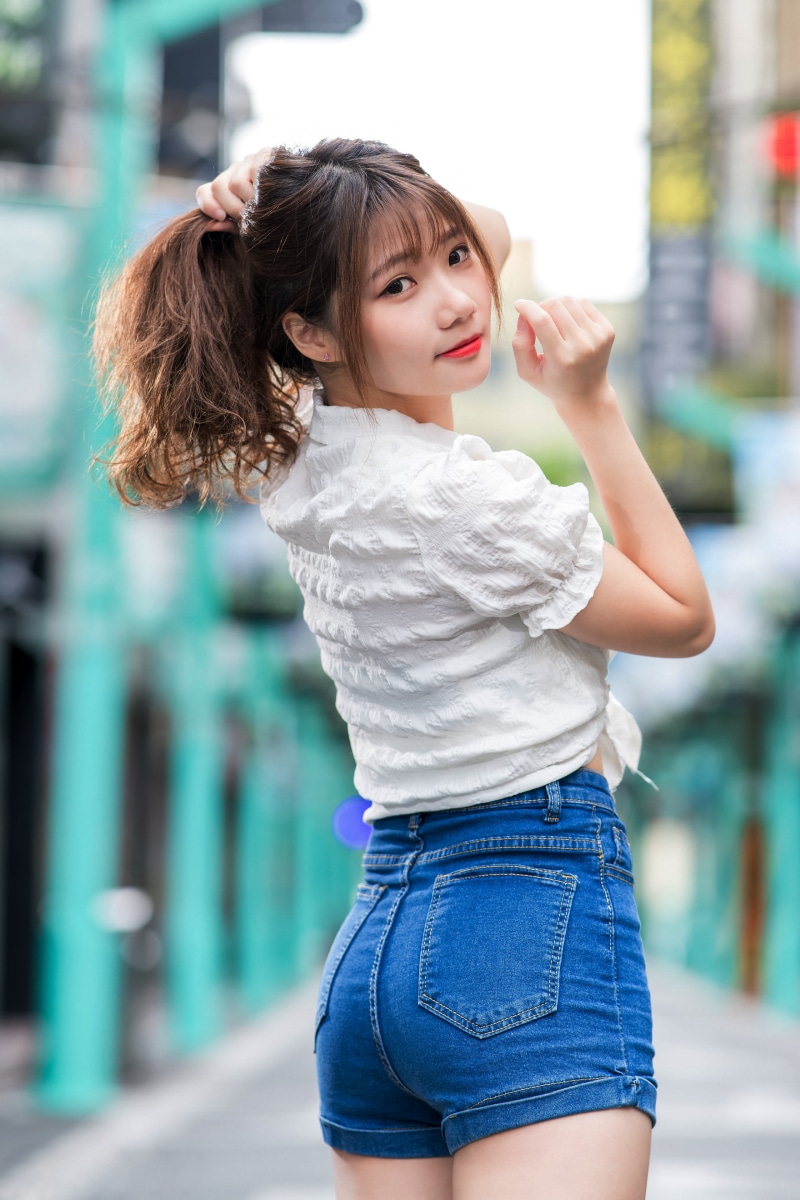 Asian woman in white blouse and denim shorts posing