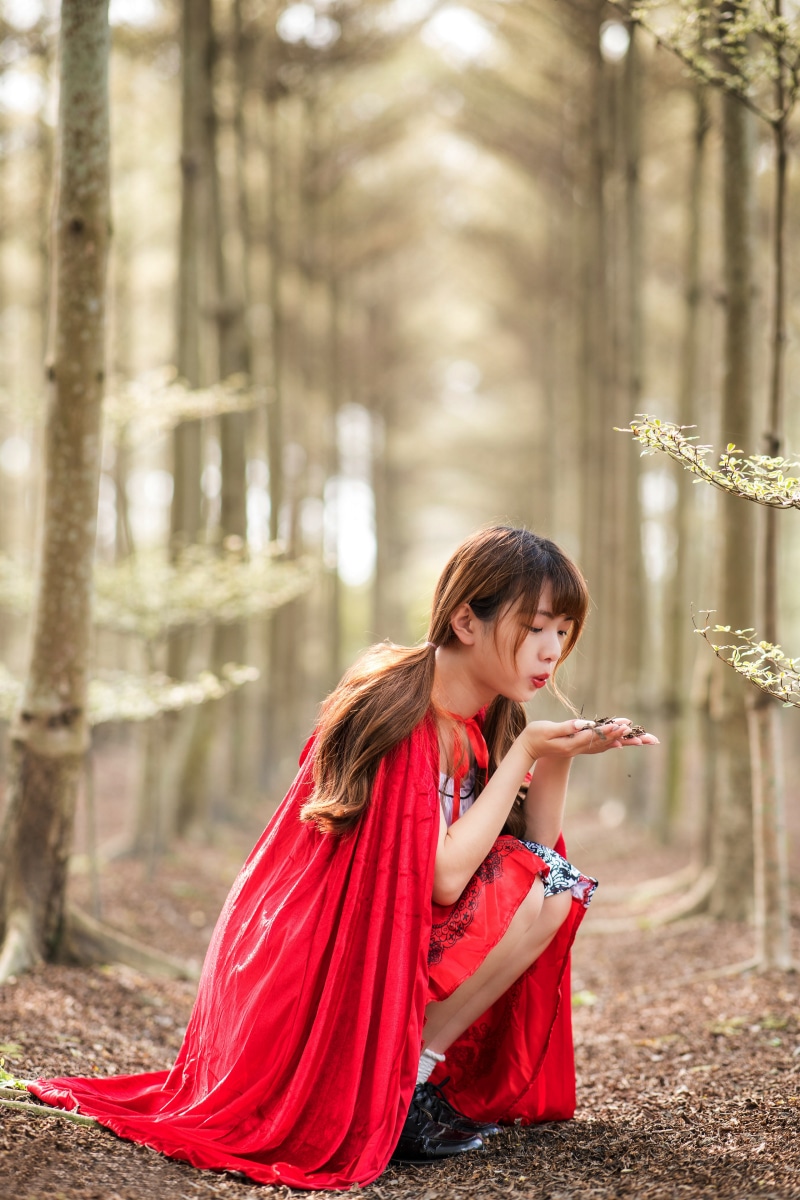 Asian girl in Red Riding Hood costume in forest