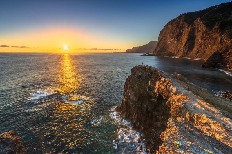 Sunset over Madeira coast with a lone figure on a cliff