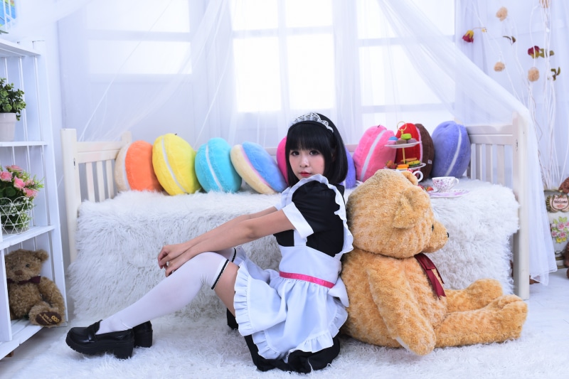 Maid girl with teddy bear and macaron pillows
