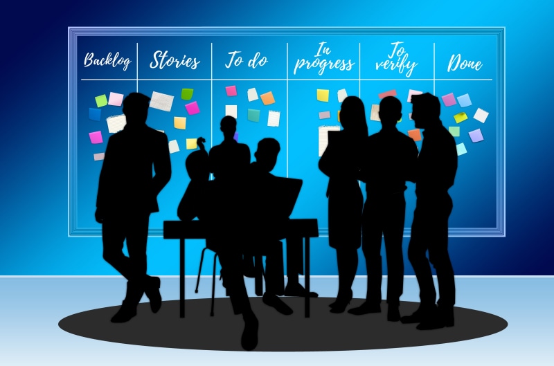 Silhouettes of people at a Kanban board