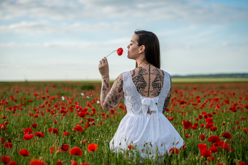 Woman with tattoos in a poppy field