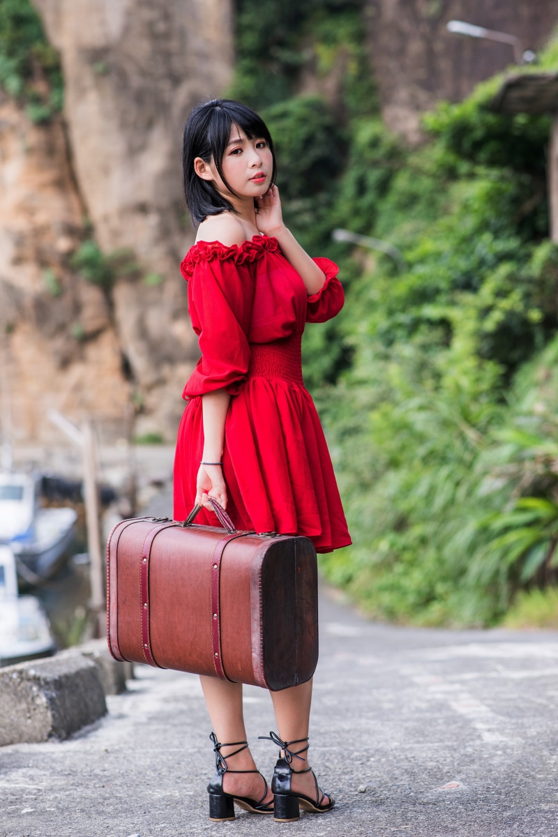 Asian girl in red dress holding suitcase
