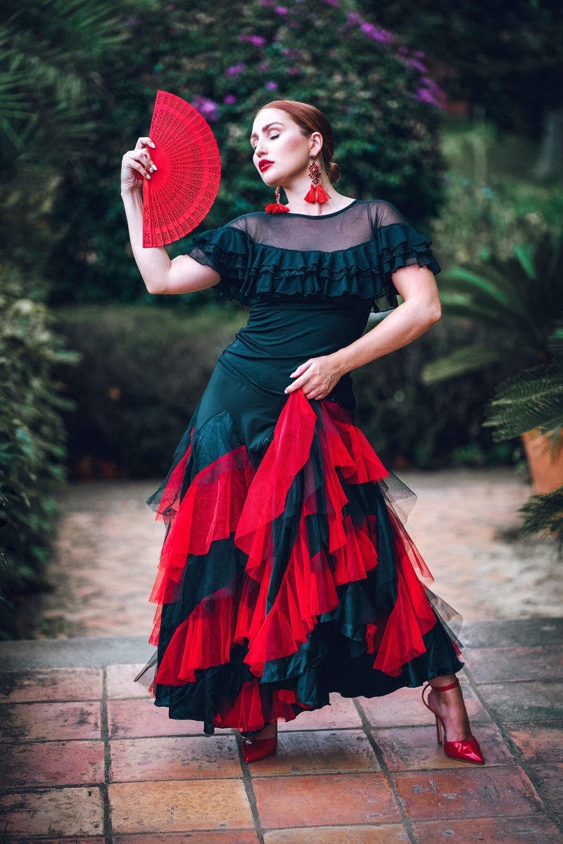 Flamenco dancer in a black and red dress holding a fan