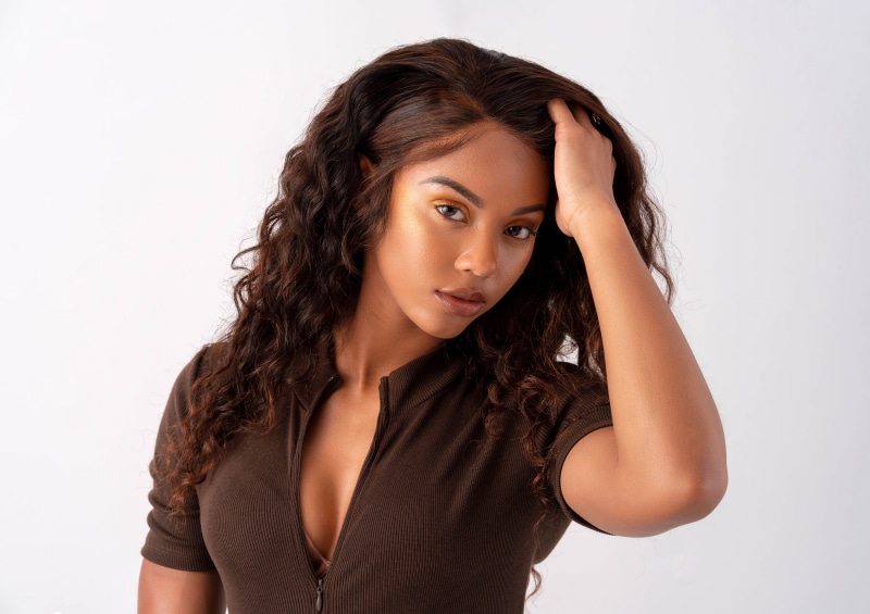 Adiva with Curly Brown Hair and Hand on Head
