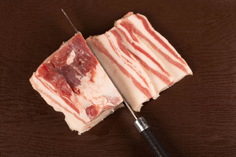 Knife slicing through a block of salo