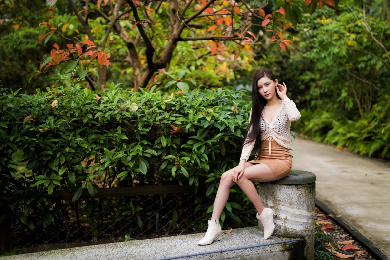 Asian woman sitting on a stone bench in a park