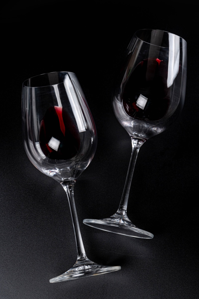 Two wine glasses filled with red wine on a black background