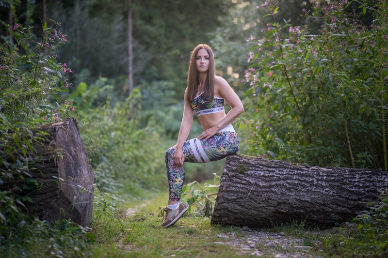 Julia-Pia sitting on a tree trunk in a forest