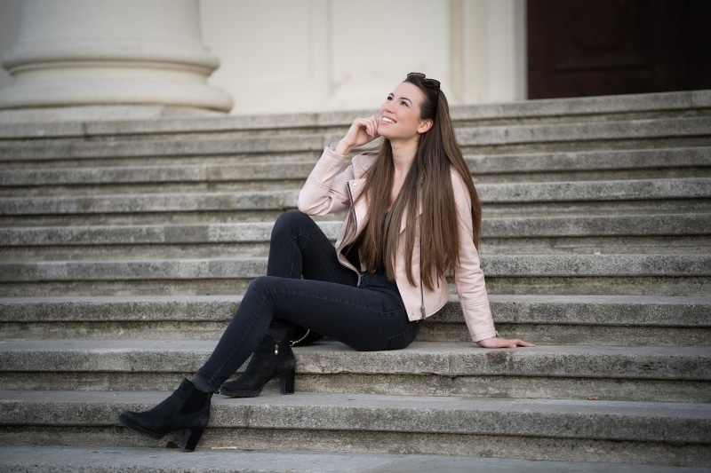 Julia sitting on stairs wearing a jacket and jeans