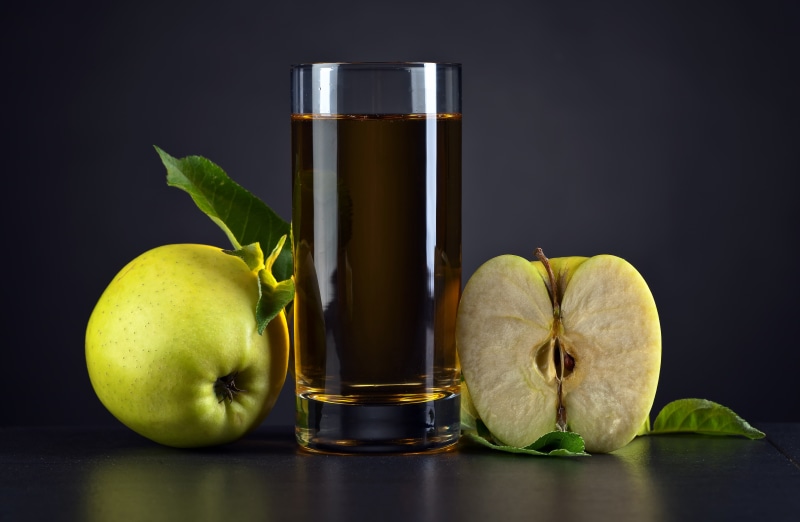 Apple juice in a highball glass with apples