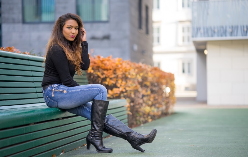 Woman in Jeans and Boots Sitting on Bench