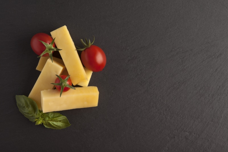 Cheese sticks with tomatoes and basil on a gray background