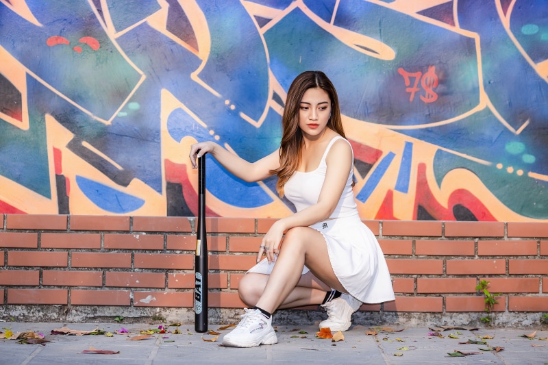 Woman with Baseball Bat Posing in Front of Graffiti Wall