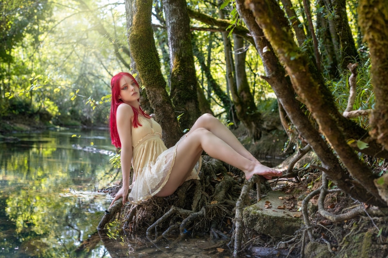 Lana sitting by a stream in a forest