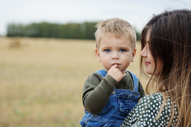 Mother holding a young boy in a field