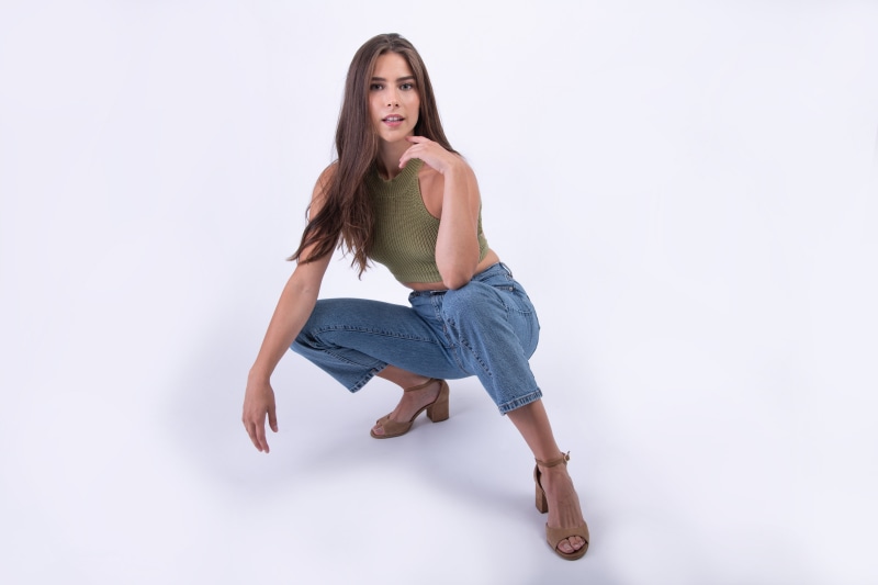 Model in green top and jeans posing