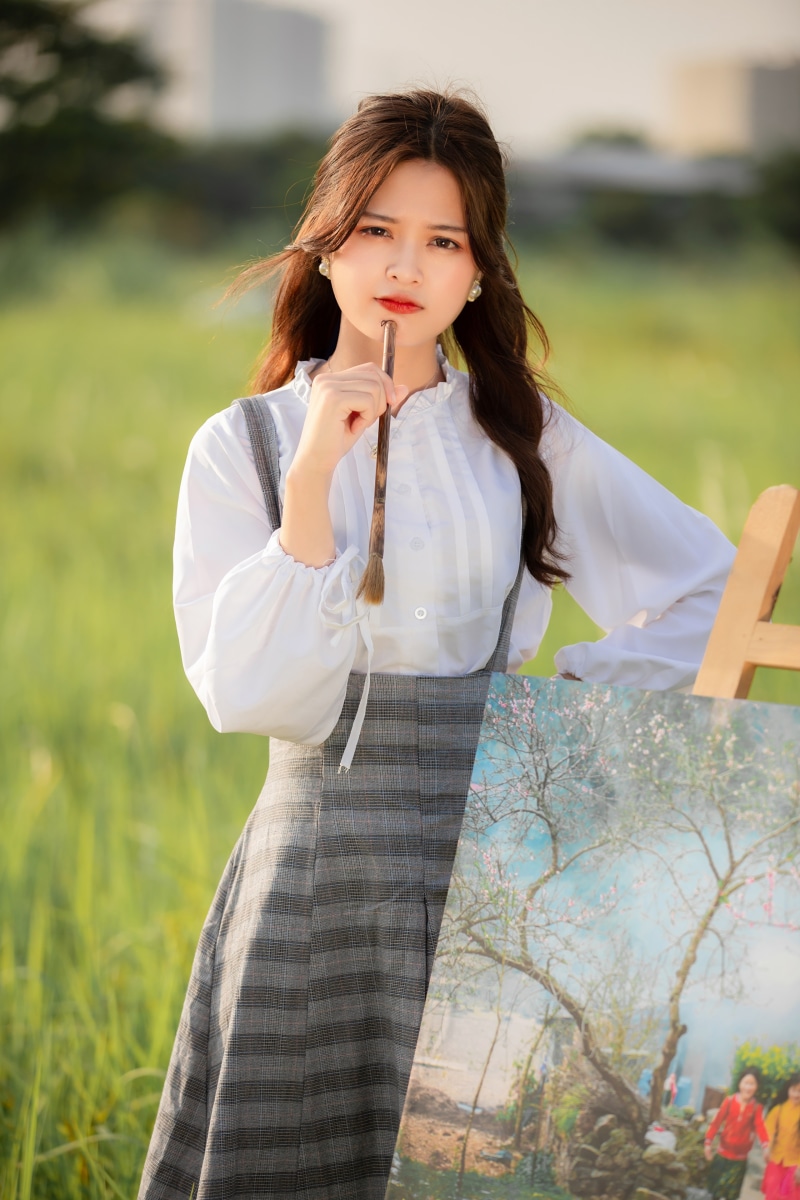 Asian woman holding paintbrush near painting