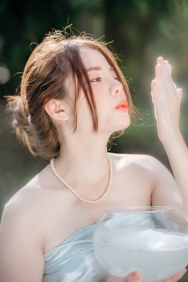 Asian woman with pearl necklace holding a bowl of bubbles