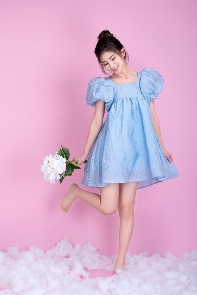 Asian girl in blue dress holding white flowers