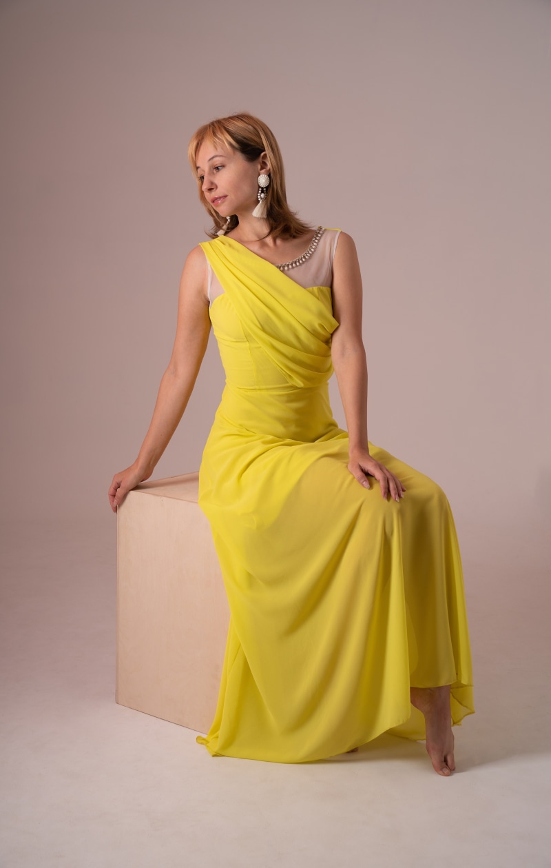 Victoria Borodinova in a yellow dress sitting on a cube