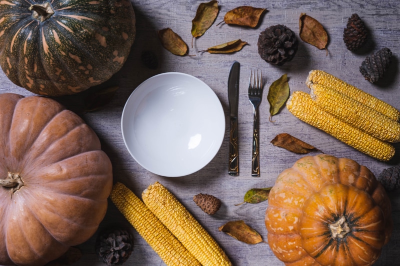Thanksgiving table setting with pumpkins, corn, and cutlery