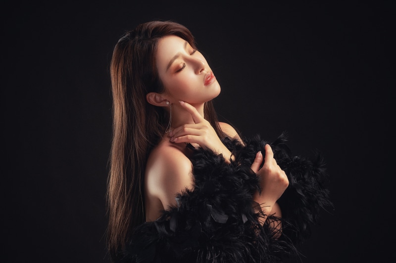 Asian woman with brown hair and black boa