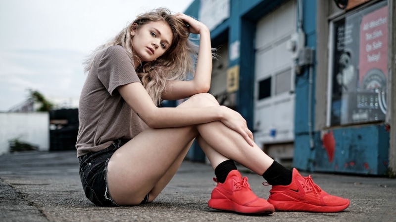Blonde girl sitting in athletic shoes and shorts