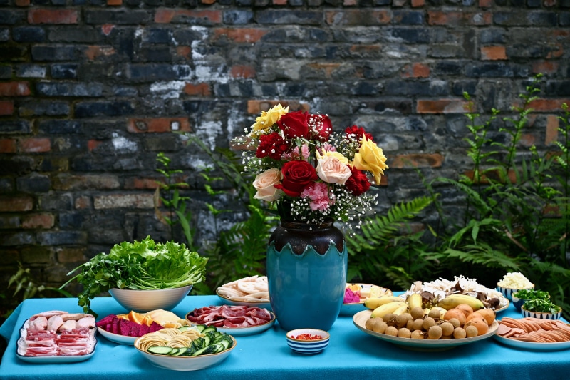 Table with food, flowers, and brick wall