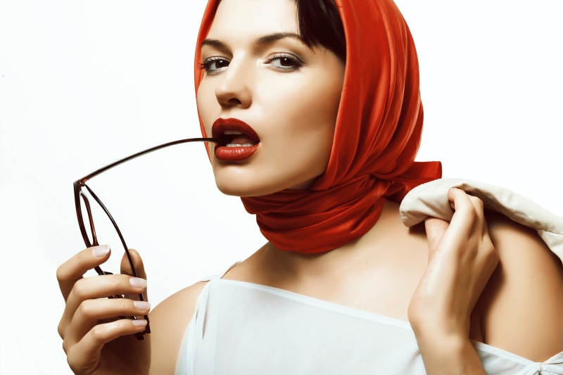 Woman with red headscarf holding glasses