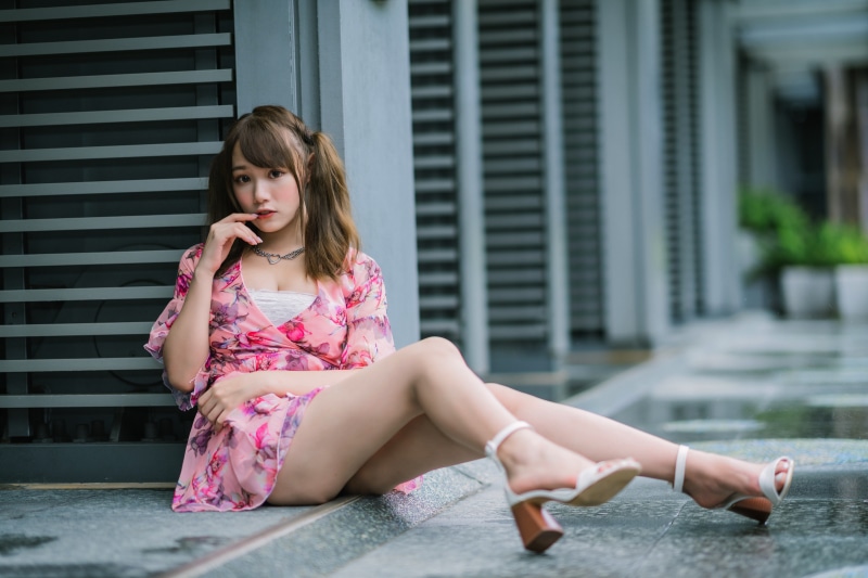 Asian woman in pink floral dress sitting outdoors