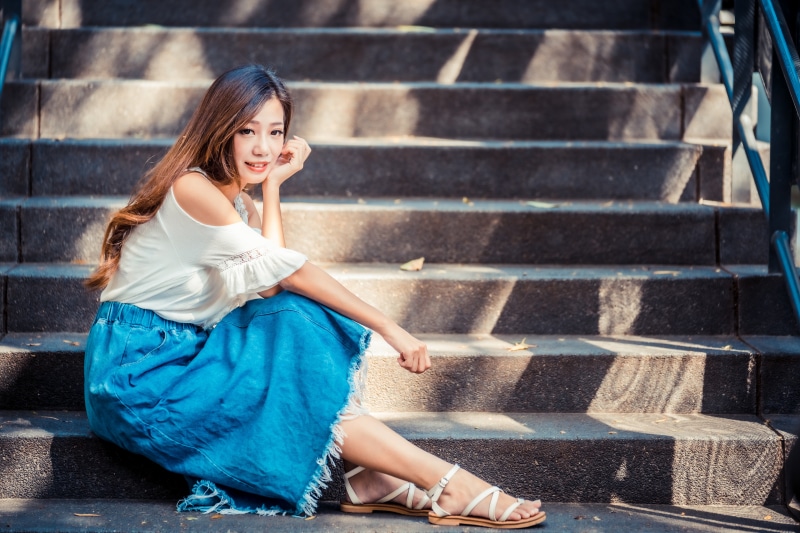 Asian woman with brown hair sitting on stairs