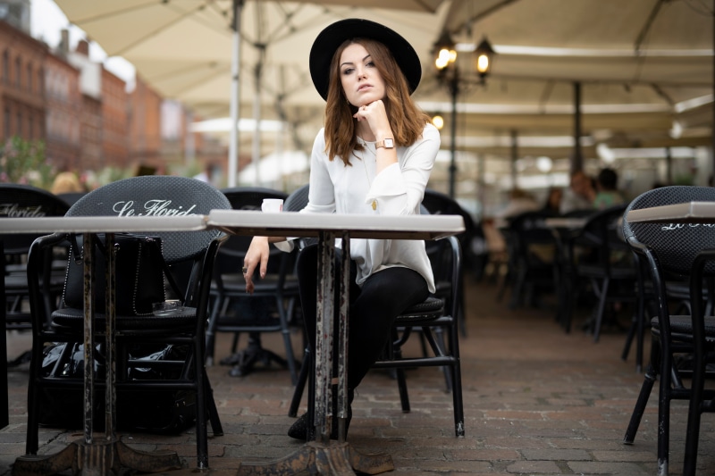 Woman in Hat Sitting at Cafe Table