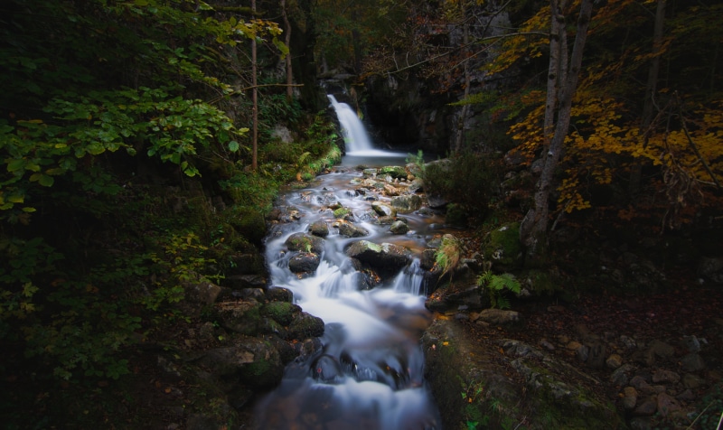 Autumn stream with waterfall and mossy stones