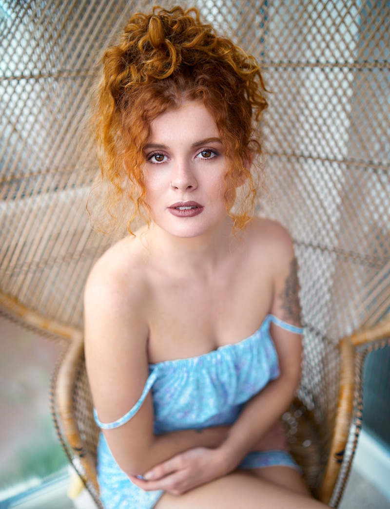 Redhead woman with curly hair sitting in a chair