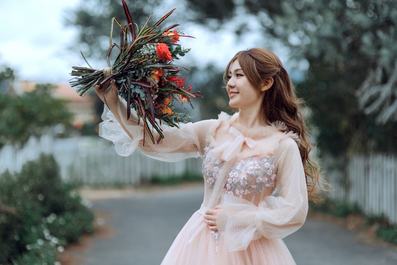 Asian woman in a pink dress holding a bouquet