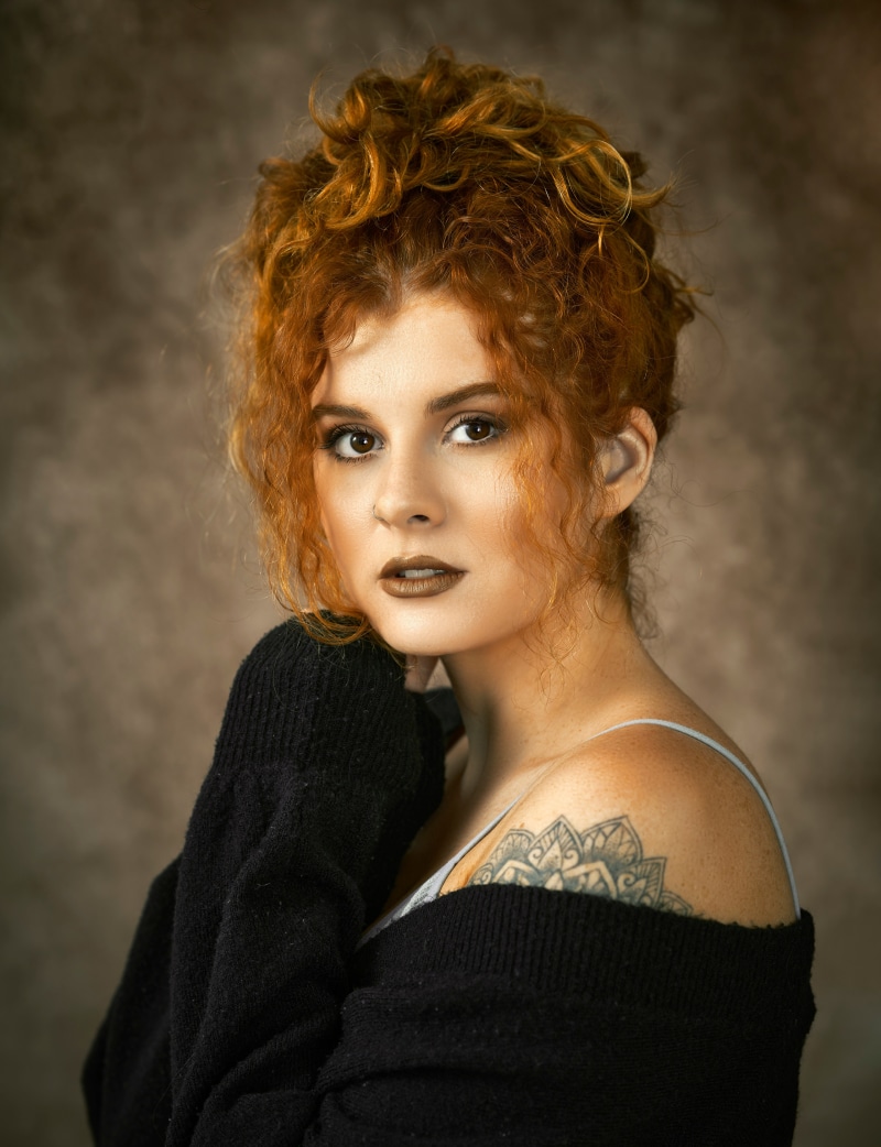 Redhead woman with curly hair and tattoo