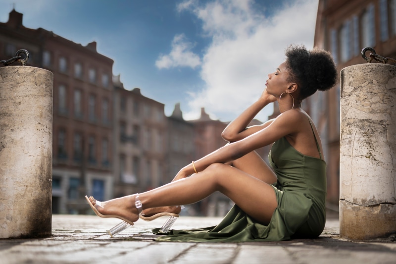 Woman in green dress sitting on cobblestone street