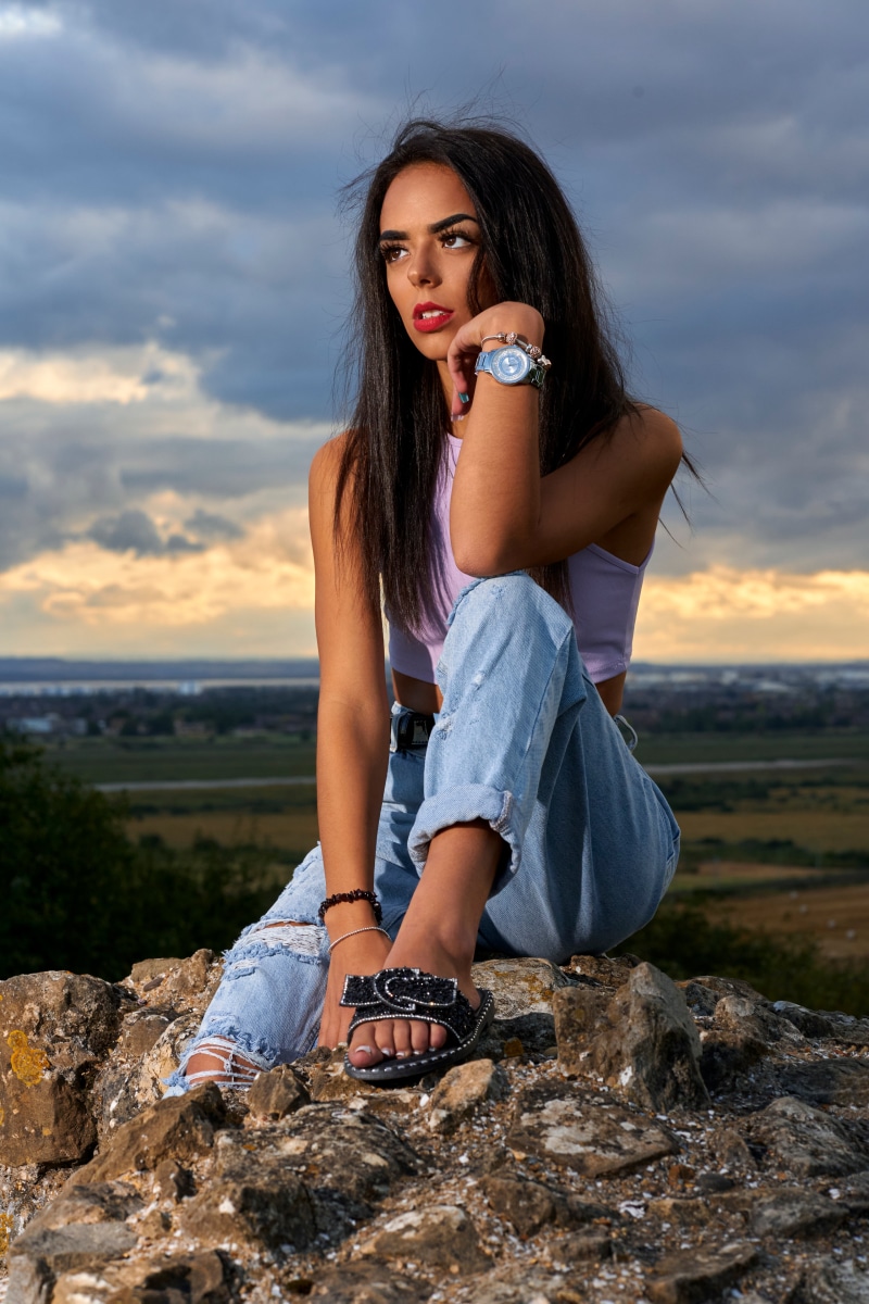 Brunette girl in jeans sitting on stones