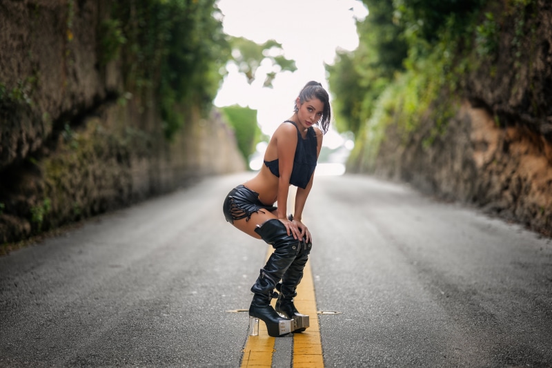 Woman in boots posing on a road