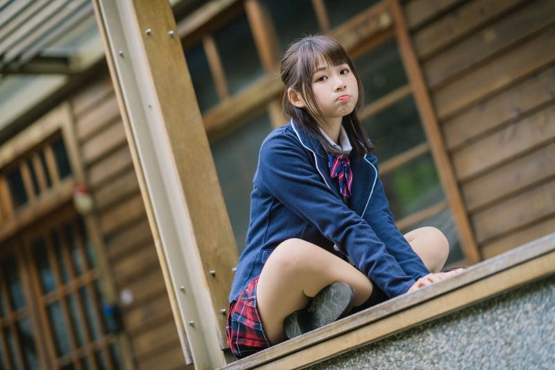 Asian schoolgirl in uniform sitting outdoors
