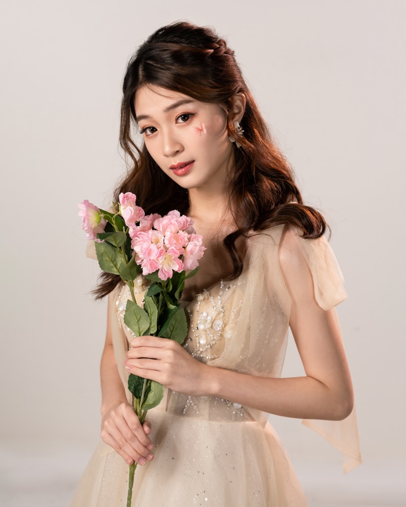 Asian woman in a dress holding pink flowers
