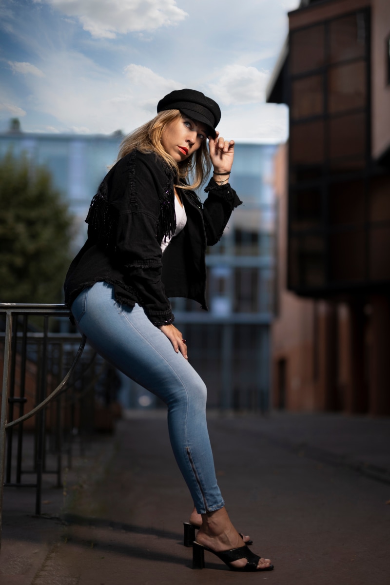 Blonde girl in jeans and baseball cap posing