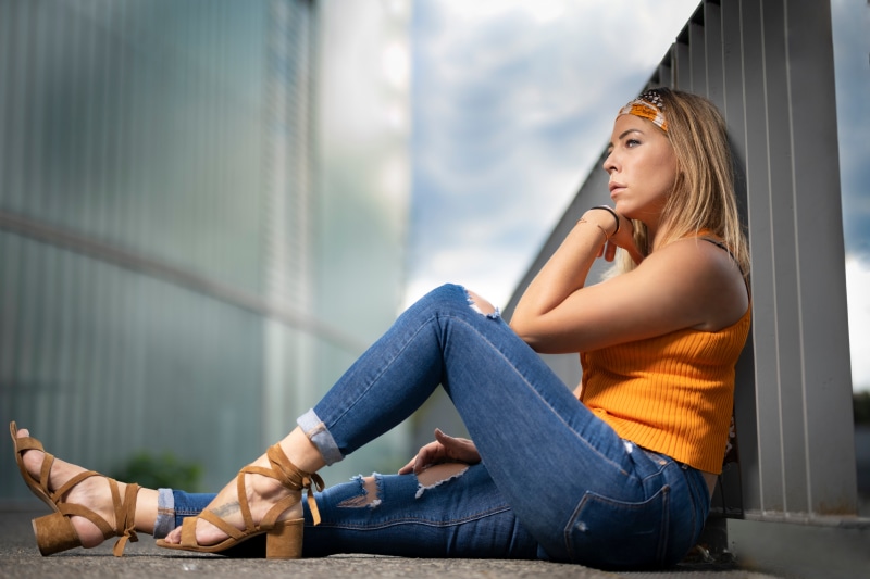 Woman in Jeans and Orange Top Sitting Outdoors